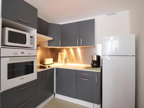une cuisine avec des armoires grises et un réfrigérateur blanc dans l'établissement T2 Mont-Dore 32m², Ascenseur, Parking, Calme, Proche Centre & Thermes - FR-1-608-91, à Le Mont-Dore