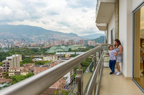 una donna e un bambino che camminano sul balcone di un edificio di Hotel Dorado La 70 a Medellín