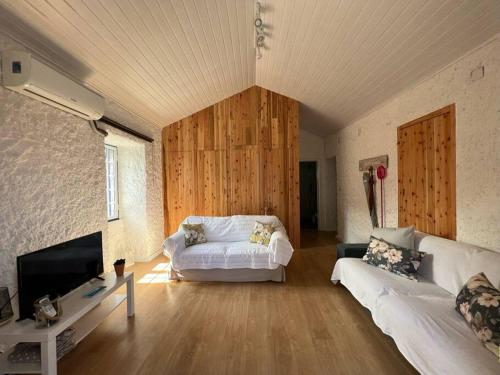 een woonkamer met een witte bank en een tv bij Vacas Felizes Villas - Casa da Bilha in Rabo de Peixe