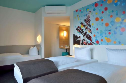 una habitación de hotel con 2 camas y un cuadro en la pared en B&B Hotel München City-Ost en Múnich