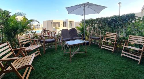 a group of chairs and an umbrella on the grass at Ain Sokhna 'Cosmopolitan' in Ain Sokhna