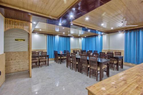 une salle à manger avec des tables, des chaises et des rideaux bleus dans l'établissement Zoz m, à Manali