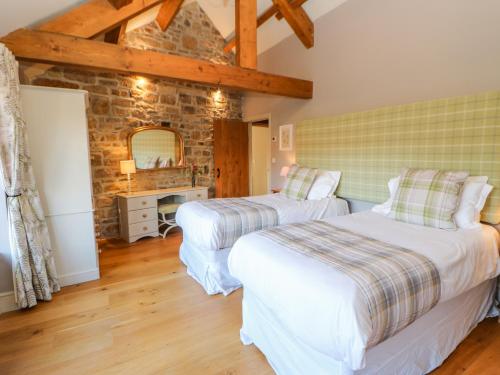 a bedroom with two beds and a stone wall at The Byre, Sedbury Park Farm in Richmond