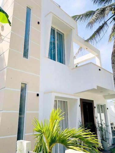 a white house with palm trees in front of it at Ayona Beach Villa in Katuneriya