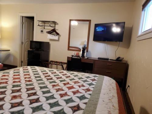 a bedroom with a bed and a desk and a television at Three Forks Lewis & Clark Motel in Three Forks