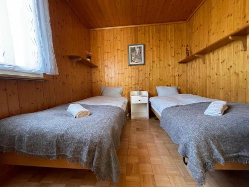 two twin beds in a room with wooden walls at Blässchopfhüsli in Nesslau