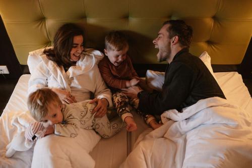 a family sitting in a bed with their children at Hotel Inn Salland in Raalte