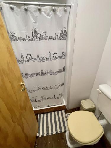 a bathroom with a toilet and a shower curtain at Mucho Bonito Hostel in Santa Fe