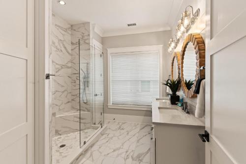 ein Badezimmer mit Dusche, Waschbecken und Spiegel in der Unterkunft Astin Cottage - 4221 Seventh Street in Saint Simons