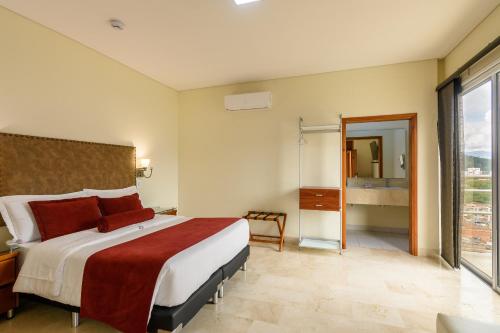 a bedroom with a large bed and a large window at Hotel Dorado La 70 in Medellín