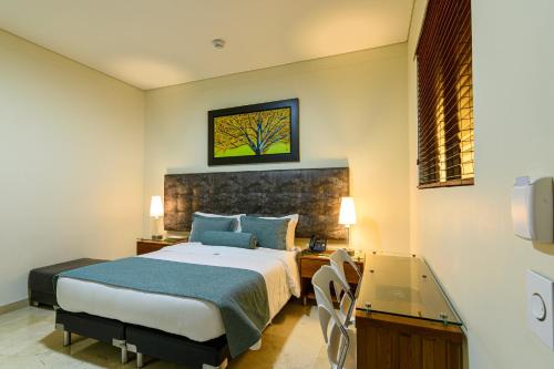 a bedroom with a bed and a desk and a window at Hotel Dorado La 70 in Medellín