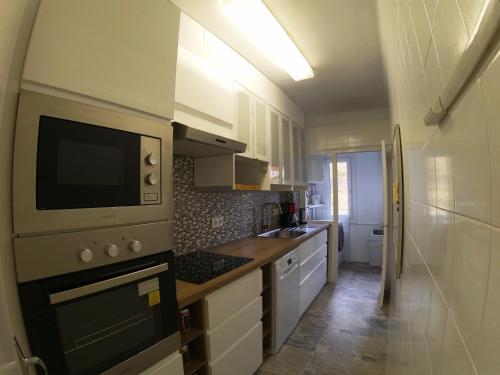 a small kitchen with white cabinets and a microwave at Soldeu Paradis Soldeu in Soldeu