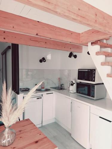une cuisine avec des placards blancs et un escalier en bois dans l'établissement Appartement avec piscine proche plages, au Cap d'Agde