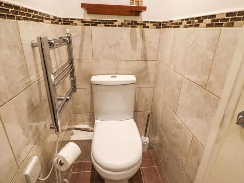 a bathroom with a toilet and a tiled wall at The Old Piggery in Keighley
