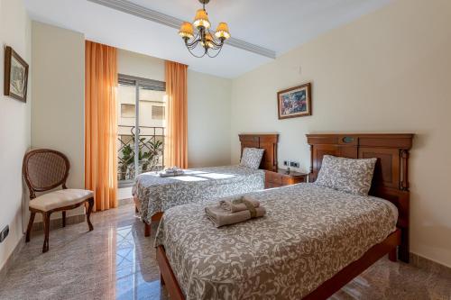 een slaapkamer met 2 bedden, een stoel en een raam bij 797 HOLIDAY RENTALS - BELLAGIO- Elegante piso para 6 a 1 min de la playa, con piscina interior y exterior, SPA con jacuzzi in Benalmádena