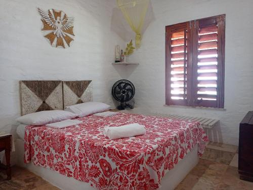 um quarto com uma cama com um cobertor vermelho e branco em Casa dos Ximenes - Beira Mar da Taíba - Ótima localização em Taíba