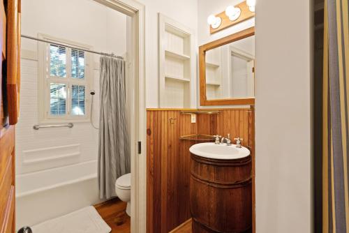 ein Badezimmer mit Waschbecken, Toilette und Spiegel in der Unterkunft Palmetto Cottage - 116 Florence Street in King City