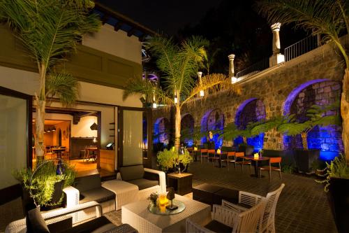 a patio with tables and chairs and palm trees at night at Aubrey Hotel Boutique in Santiago