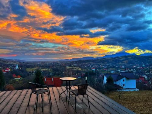 a table and chairs on a wooden deck with a sunset at Tiny House Retreat Bran in Bran