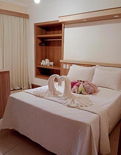dos cisnes acostados en una cama en un dormitorio en Hotel Lux, en Poços de Caldas
