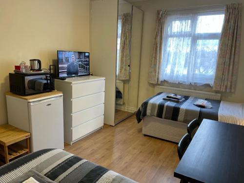 a room with a bedroom with a bed and a television at Gladstone Lodge in London