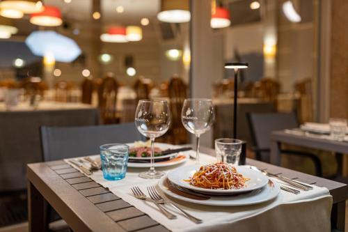 a table with two plates of pasta and wine glasses at Hotel Imperial ***S in Garda