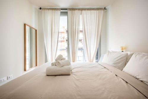 a white bed with towels on it in front of a window at LUVI - De Rolandi - Il Cortile Milano in Milan