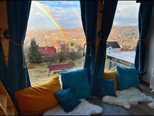 una ventana con sofá y vistas a un arco iris en Tiny House Retreat Bran, en Bran