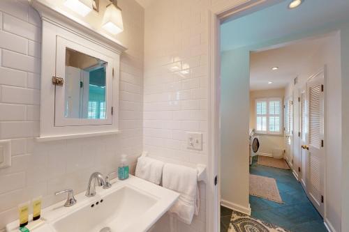a white bathroom with a sink and a mirror at Latitude Adjustment - 4311 Ninth Street in Saint Simons Island