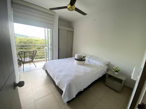 a white bedroom with a bed and a balcony at Ven a recargar energías. in Girardot