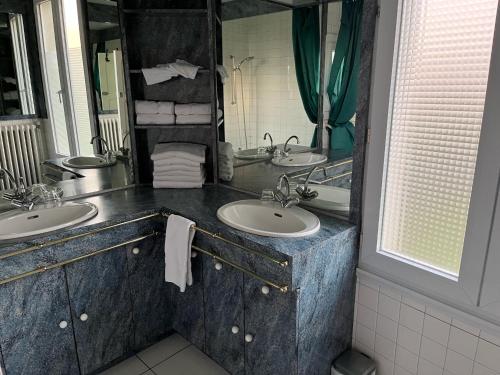 un bagno con due lavandini e un grande specchio di Entre mûres et châtaignes a Les Châtelliers-Châteaumur