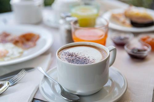 a cup of coffee on a table with plates of food at Hotel Imperial ***S in Garda