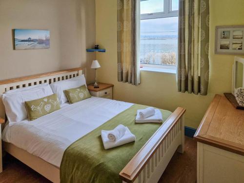 a bedroom with a large bed with towels on it at Bankswood Cottage in Ruthwell