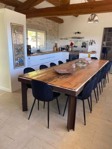 une table en bois dans une cuisine avec des chaises autour de celle-ci dans l'établissement Mas en Pierre avec Piscine, Jacuzzi et sauna, à Saint-Sauveur-de-Cruzières