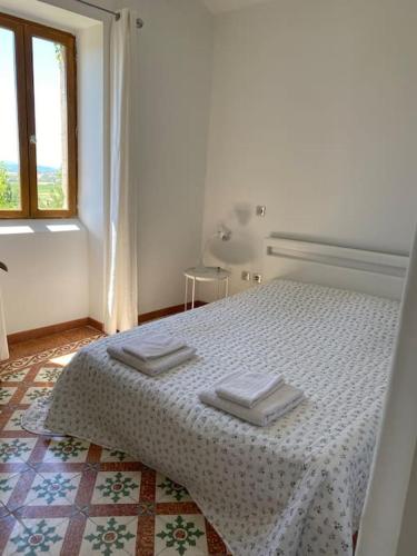 une chambre blanche avec un lit avec deux serviettes dessus dans l'établissement Mas en Pierre avec Piscine, Jacuzzi et sauna, à Saint-Sauveur-de-Cruzières