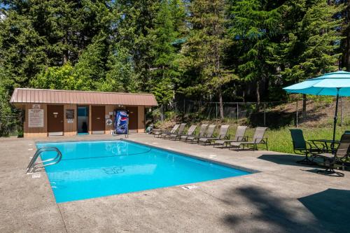 a swimming pool with chairs and an umbrella at Escape to Ptarmigan Village 47 in Whitefish
