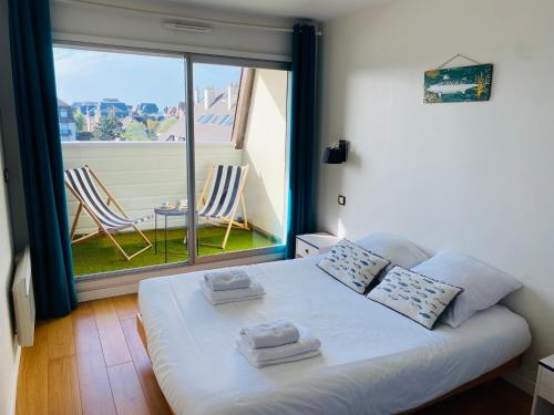 une chambre avec un lit blanc avec une grande fenêtre dans l'établissement Le Balbec vue sur mer, à Cabourg