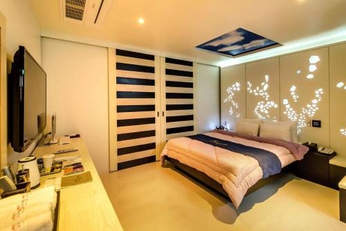 Dormitorio con cama, escritorio y TV en Gyorae Drive-in Motel en Jeju