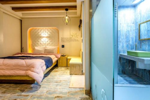 a bedroom with a bed and a bathroom with a sink at Gyorae Drive-in Motel in Jeju