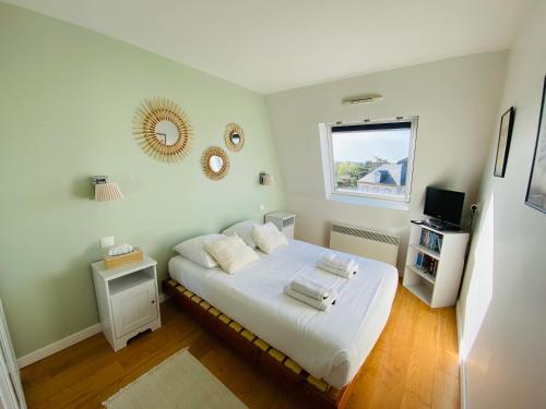 une chambre avec un lit avec des draps blancs et une fenêtre dans l'établissement Le Balbec vue sur mer, à Cabourg