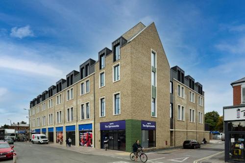 a building on a street with a person riding a bike at The Spireworks Oxford in Oxford