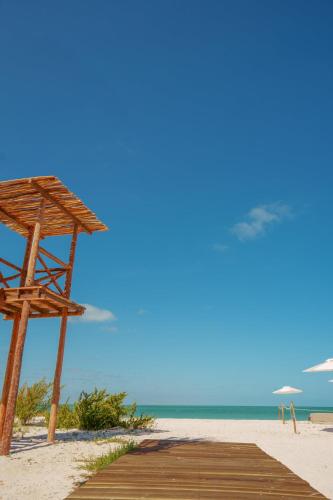 a wooden path to the beach with a parasol at Naay Boutique Hotel Holbox in Holbox Island