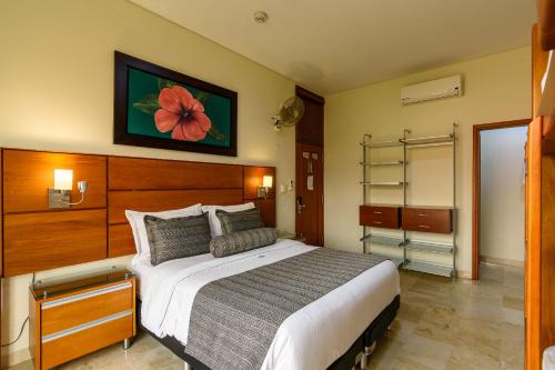 a bedroom with a large bed with a flower painting on the wall at Hotel Dorado La 70 in Medellín