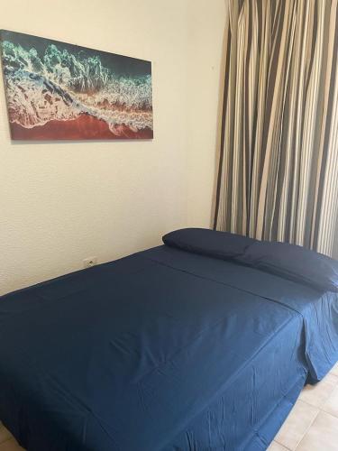 a bedroom with a blue bed with a painting on the wall at DORY HOUSE LOS CRISTIANOS in Los Cristianos