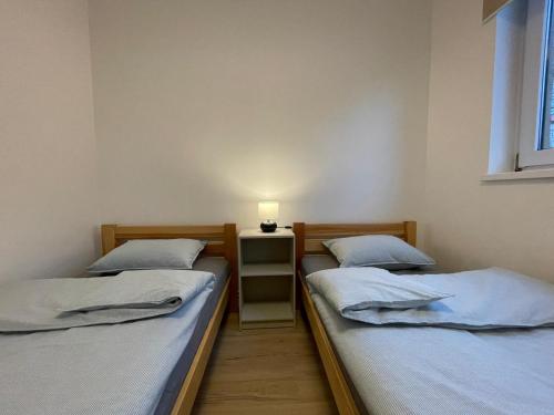 two beds in a room with a lamp on a table at APARTAMENTY GUZIK 22 in Krosno