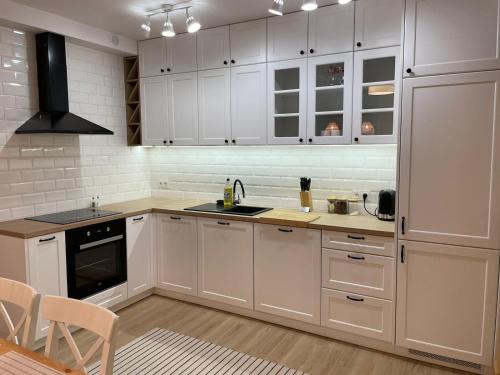 a kitchen with white cabinets and a sink and a stove at APARTAMENTY GUZIK 22 in Krosno