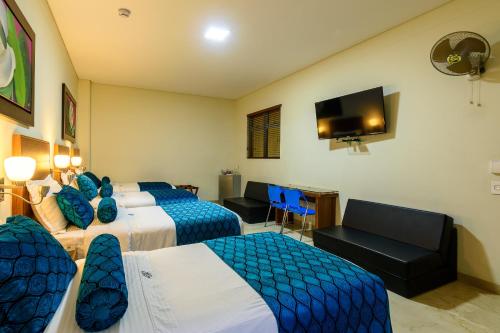 a hotel room with three beds and a flat screen tv at Hotel Dorado La 70 in Medellín