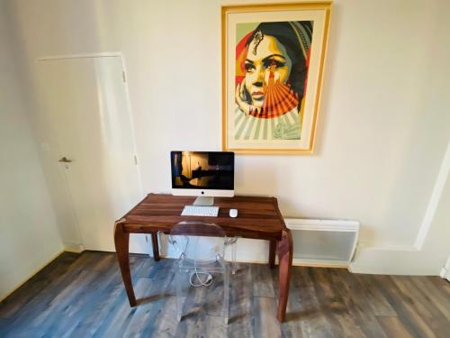 a desk with a computer and a painting on the wall at Hôtel Particulier Le 28 - Spa & Art Luxury Design by Alain Ducasse in Aix-en-Provence
