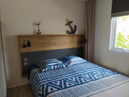 a bedroom with a bed with a blue and white comforter at Mobile Home tout confort C13 Domaine de Lanniron in Quimper