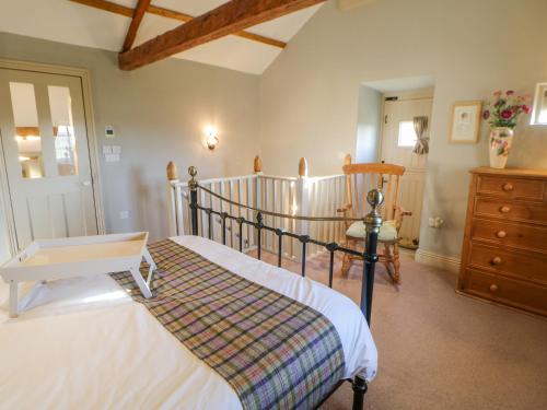 a bedroom with two beds and a chair at The Stable, Sedbury Park Farm in Gilling